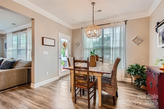 dining area with a chandelier, ornamental molding, light wood-style flooring, and baseboards