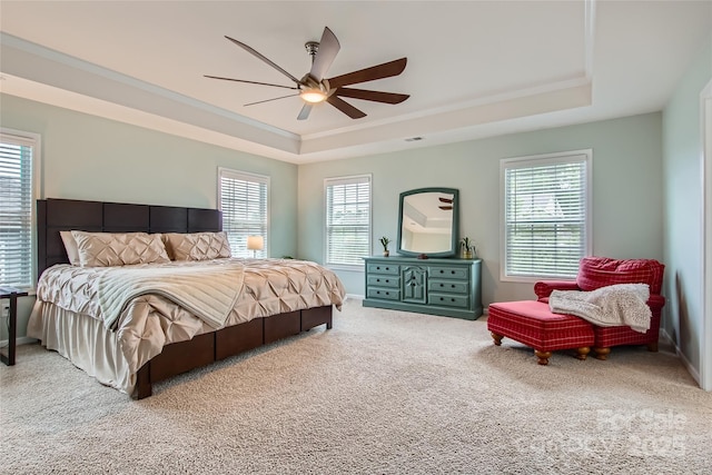 bedroom with a raised ceiling, carpet flooring, ornamental molding, a ceiling fan, and baseboards
