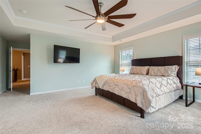 bedroom with a raised ceiling, crown molding, carpet flooring, baseboards, and ceiling fan