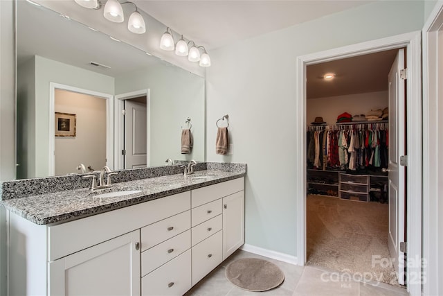 bathroom with double vanity, a spacious closet, baseboards, and tile patterned flooring