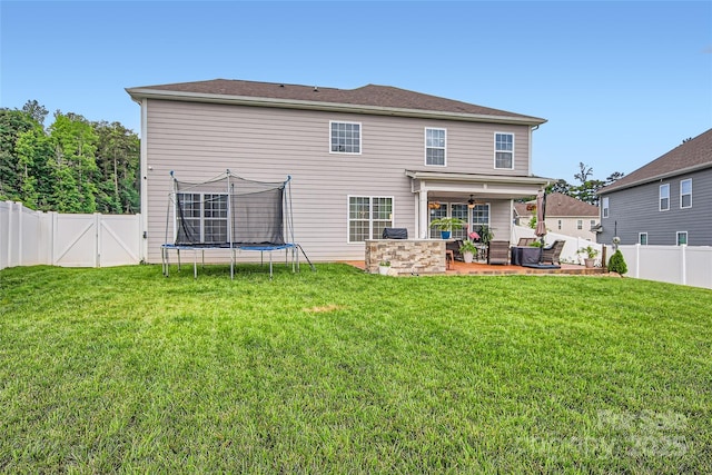 back of property featuring a patio, a ceiling fan, and a trampoline