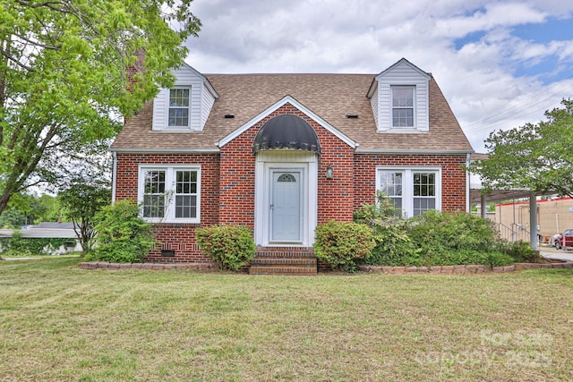 new england style home with brick siding, a front lawn, and roof with shingles