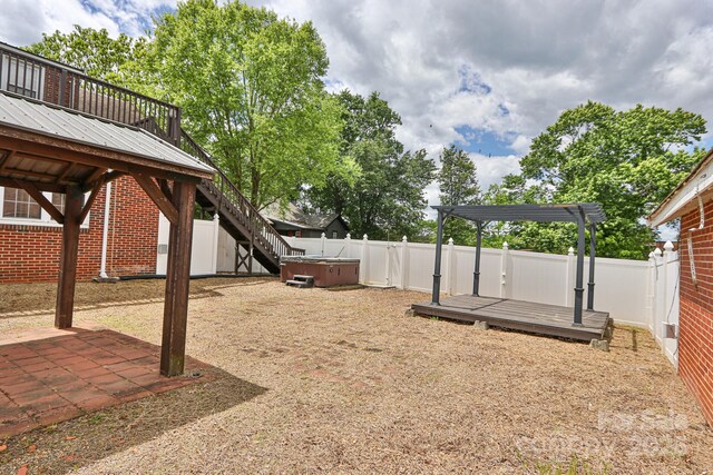 fenced backyard featuring a hot tub, a deck, and a patio