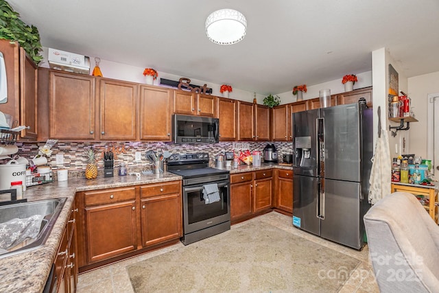 kitchen with appliances with stainless steel finishes, brown cabinetry, a sink, and tasteful backsplash