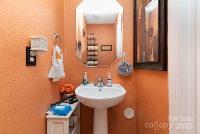 bathroom featuring a textured wall and a sink