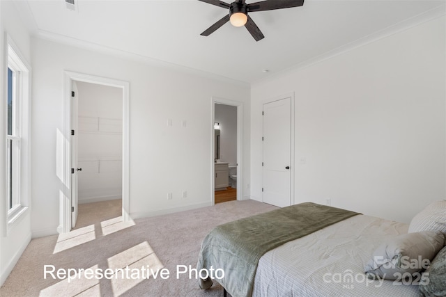 carpeted bedroom with a walk in closet, ensuite bath, baseboards, and ceiling fan