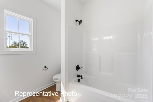 bathroom featuring toilet, wood finished floors, baseboards, and shower / bath combination
