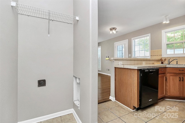 kitchen with dishwasher, tile counters, a sink, tasteful backsplash, and brown cabinets
