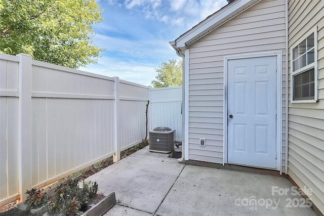 view of patio with fence, central AC, and an outbuilding