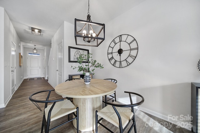 dining space with baseboards, dark wood-style flooring, and a chandelier