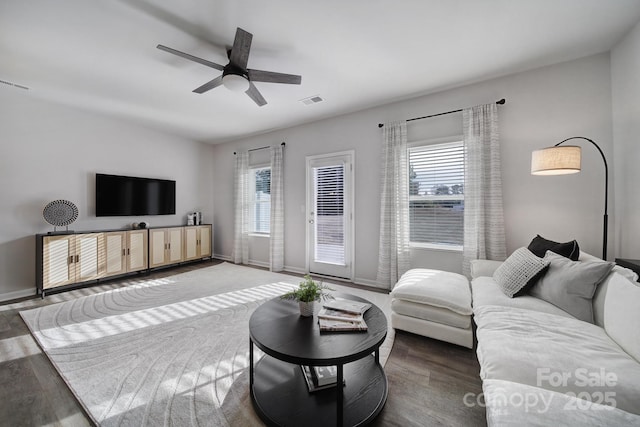 living area with healthy amount of natural light, wood finished floors, ceiling fan, and baseboards