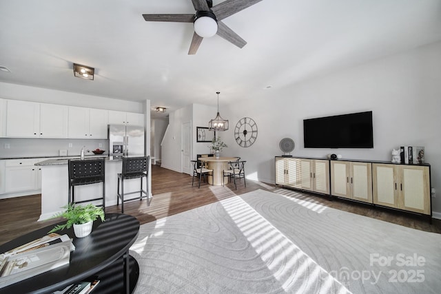 living room with dark wood finished floors, ceiling fan, baseboards, and a chandelier