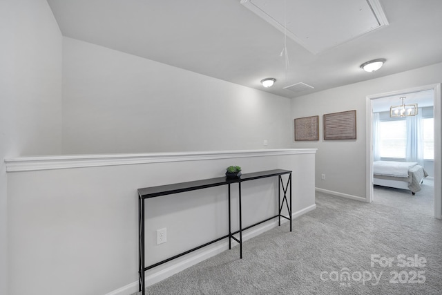 hall with attic access, carpet floors, and baseboards
