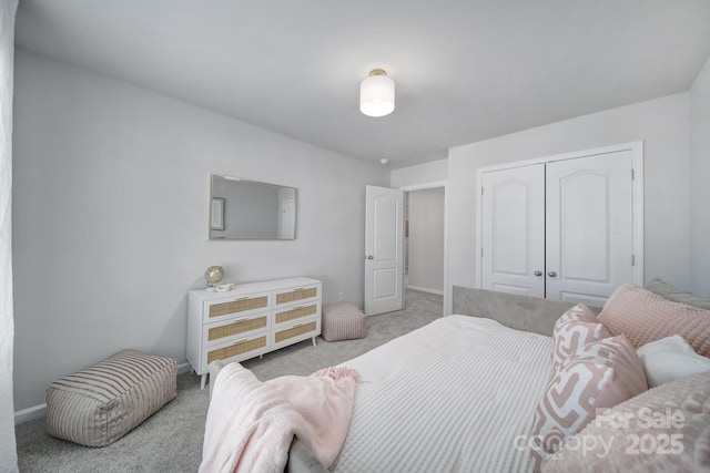 carpeted bedroom with a closet and baseboards