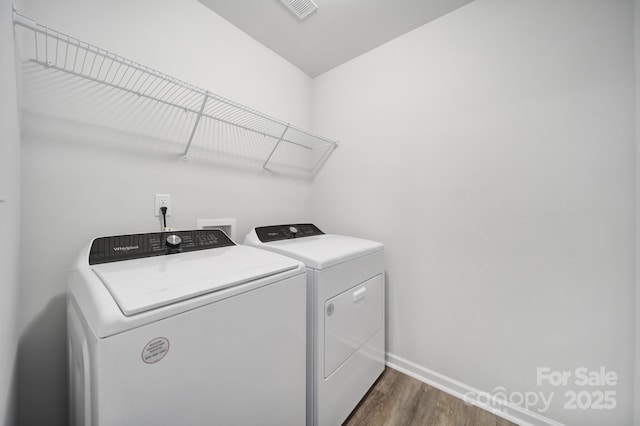 laundry room with washing machine and clothes dryer, dark wood-type flooring, and baseboards