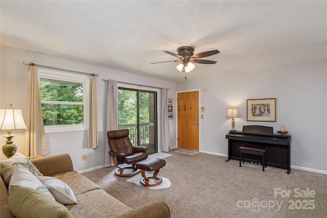 living area featuring ceiling fan, baseboards, and carpet floors