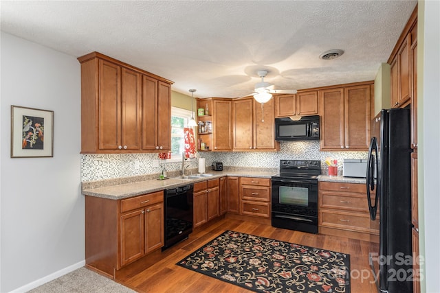 kitchen featuring black appliances, a sink, brown cabinets, backsplash, and a textured ceiling