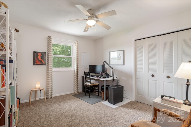 carpeted office space with ceiling fan and baseboards