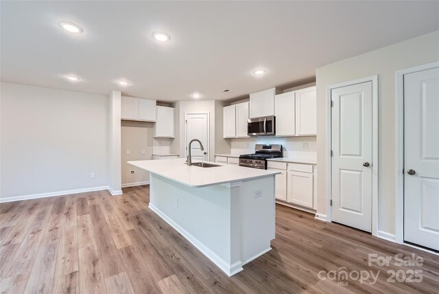 kitchen featuring appliances with stainless steel finishes, a sink, white cabinets, an island with sink, and recessed lighting