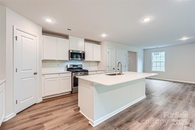 kitchen with stainless steel appliances, a sink, light wood-style floors, white cabinets, and recessed lighting