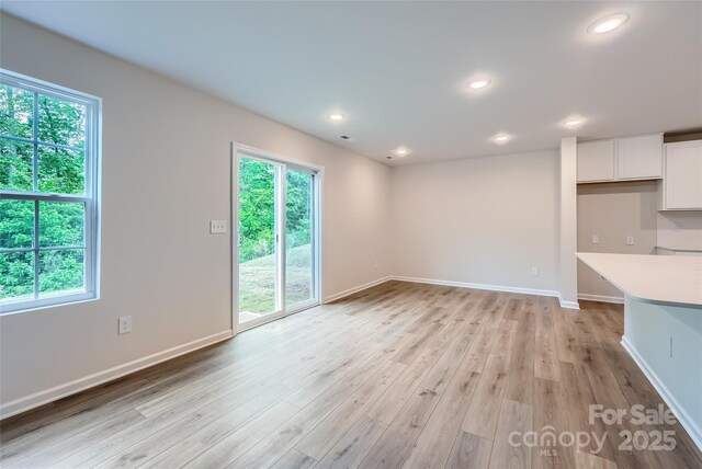unfurnished living room featuring healthy amount of natural light, light wood finished floors, baseboards, and recessed lighting