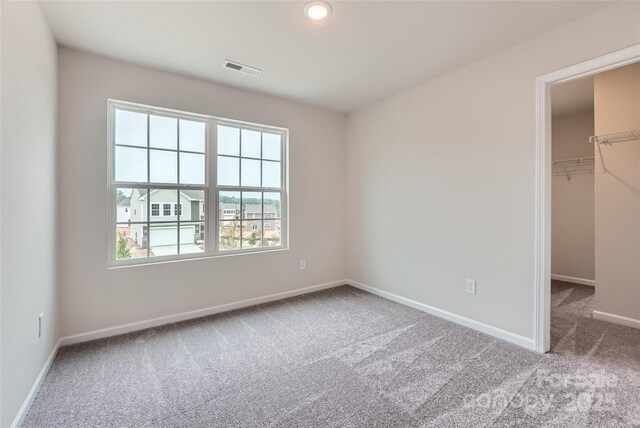 unfurnished bedroom featuring carpet, a spacious closet, baseboards, and a closet