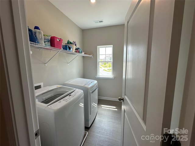 clothes washing area with washer and clothes dryer, baseboards, and dark tile patterned floors