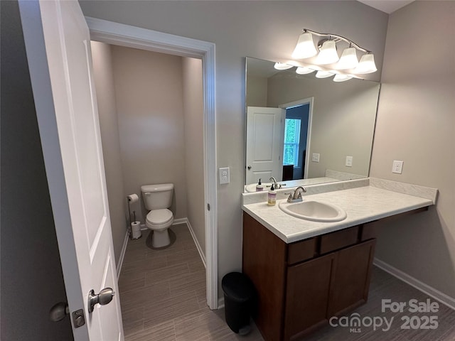 bathroom featuring baseboards, toilet, and vanity