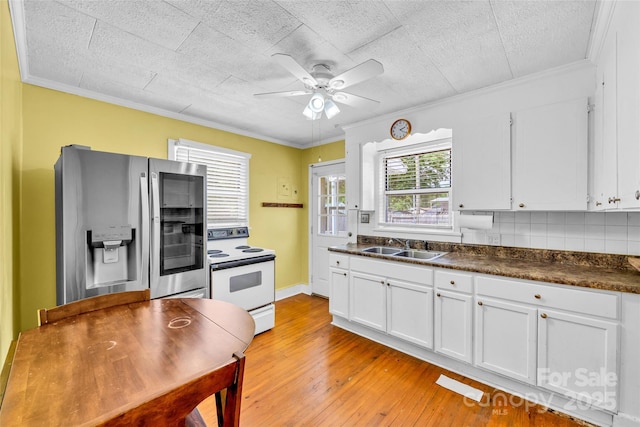 kitchen with white range with electric stovetop, stainless steel fridge, dark countertops, ceiling fan, and white cabinets