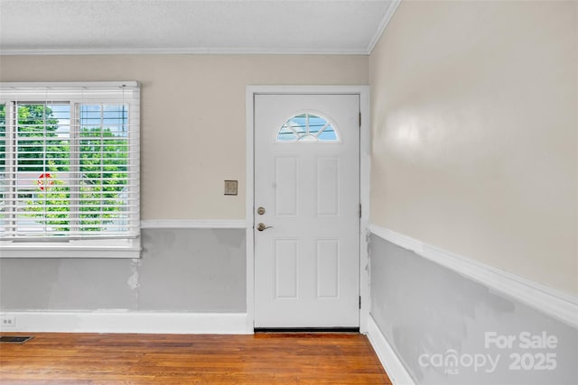 entrance foyer featuring wood finished floors, baseboards, and ornamental molding
