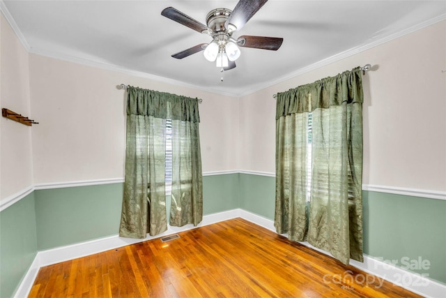 empty room featuring wood finished floors, baseboards, a ceiling fan, and crown molding
