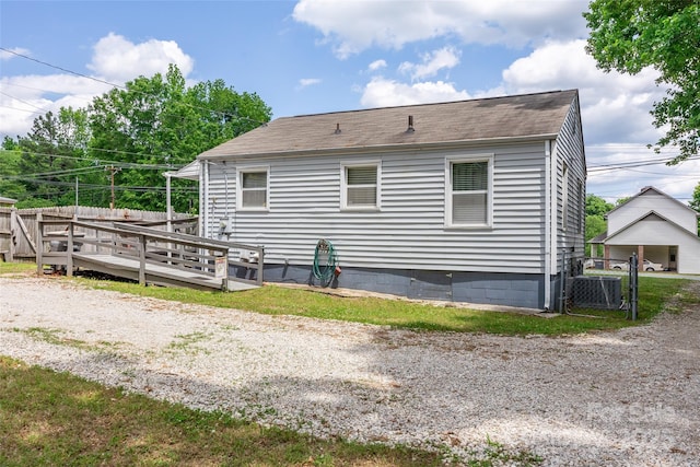 back of house with a deck, a shingled roof, cooling unit, and fence