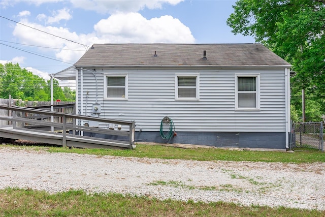 rear view of house with fence, a shingled roof, and a deck