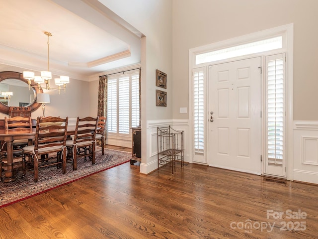 7040 Edenderry Dr, Charlotte, NC 28270 - foyer with a chandelier, wood finished floors, a wainscoted wall, crown molding, and a decorative wall
