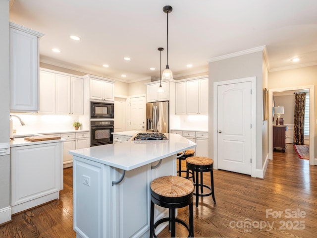 7040 Edenderry Dr, Charlotte, NC 28270 - kitchen with black appliances, crown molding, a kitchen bar, a kitchen island, and white cabinets