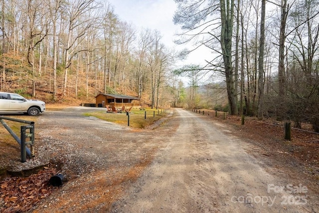 view of dirt / gravel road featuring a view of trees
