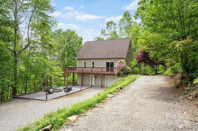 25 Licklog Ridge Rd, Fairview, NC 28730 - view of front of property featuring a wooden deck, dirt driveway, an outdoor fire pit, a shingled roof, and a garage