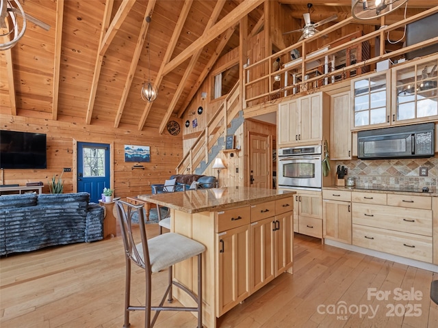 16 Sutton Knob Rd, Maggie Valley, NC 28751 - kitchen featuring stainless steel oven, wood walls, black microwave, wood ceiling, and open floor plan