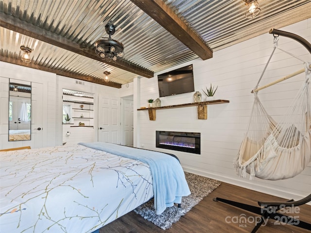16 Sutton Knob Rd, Maggie Valley, NC 28751 - bedroom with wood finished floors, beam ceiling, a glass covered fireplace, and wood walls