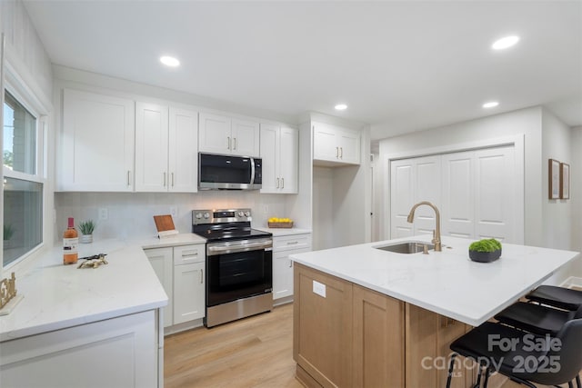 4042 Uppergate Ln, Charlotte, NC 28215 - kitchen featuring appliances with stainless steel finishes, a sink, light wood-style floors, recessed lighting, and white cabinets