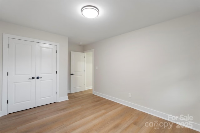 4042 Uppergate Ln, Charlotte, NC 28215 - unfurnished bedroom featuring baseboards, light wood-style flooring, and a closet