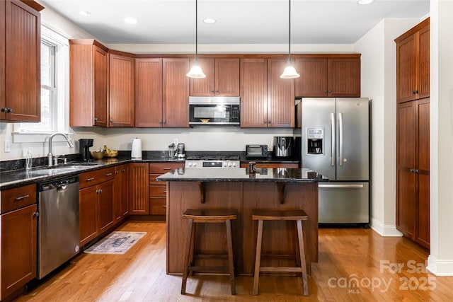 4 Yellow Owl Ct, Biltmore Lake, NC 28715 - kitchen featuring appliances with stainless steel finishes, a sink, light wood-style flooring, a kitchen island, and a breakfast bar area