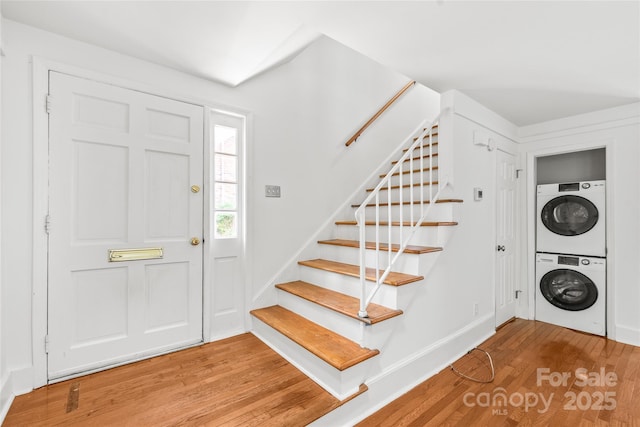 entrance foyer featuring stacked washer / drying machine, stairs, and wood finished floors