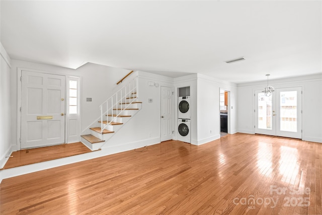 entryway with stacked washer / dryer, light wood finished floors, stairway, and baseboards