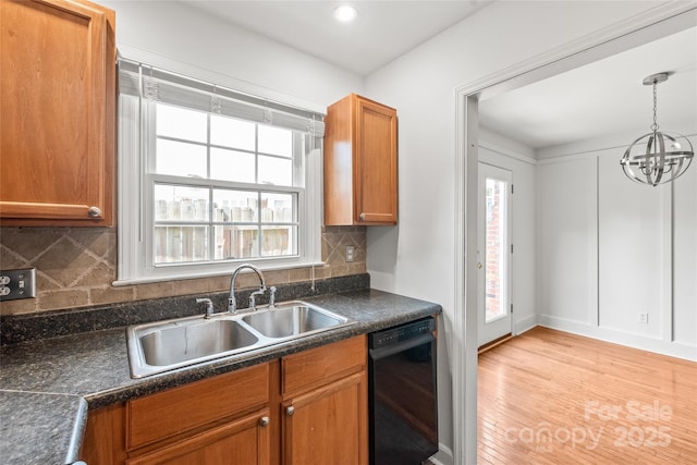 kitchen featuring dishwasher, a sink, dark countertops, brown cabinets, and light wood finished floors