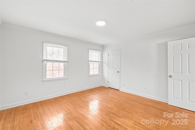 empty room with ornamental molding, light wood finished floors, and baseboards