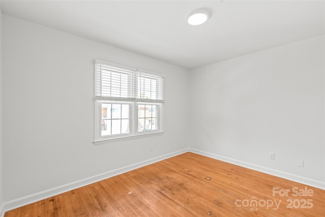 spare room featuring baseboards and light wood-style floors