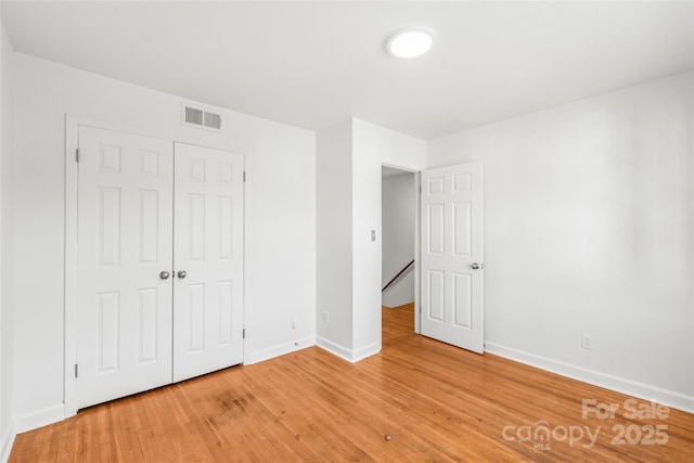 unfurnished bedroom featuring baseboards, light wood-style floors, and a closet