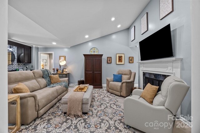 living area featuring vaulted ceiling, recessed lighting, a fireplace, and wood finished floors