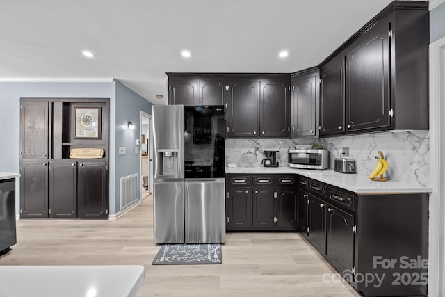 kitchen with appliances with stainless steel finishes, dark cabinetry, light countertops, backsplash, and recessed lighting